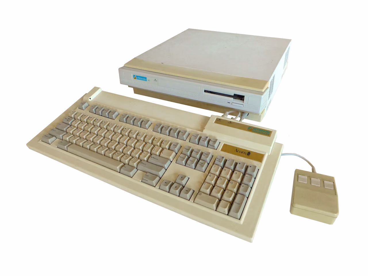 A cream Acorn Archimedes A310 photographed against white: a flat system box with a floppy slot, a separate keyboard in front of it and a three-button mouse to the right.
