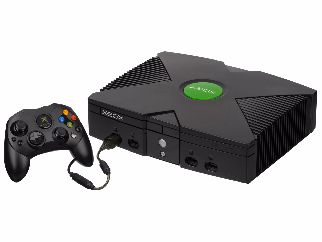A large black Microsoft Xbox photographed against white, a green jeweled X molded into its ridged lid, with a black Xbox controller plugged into the front left port.