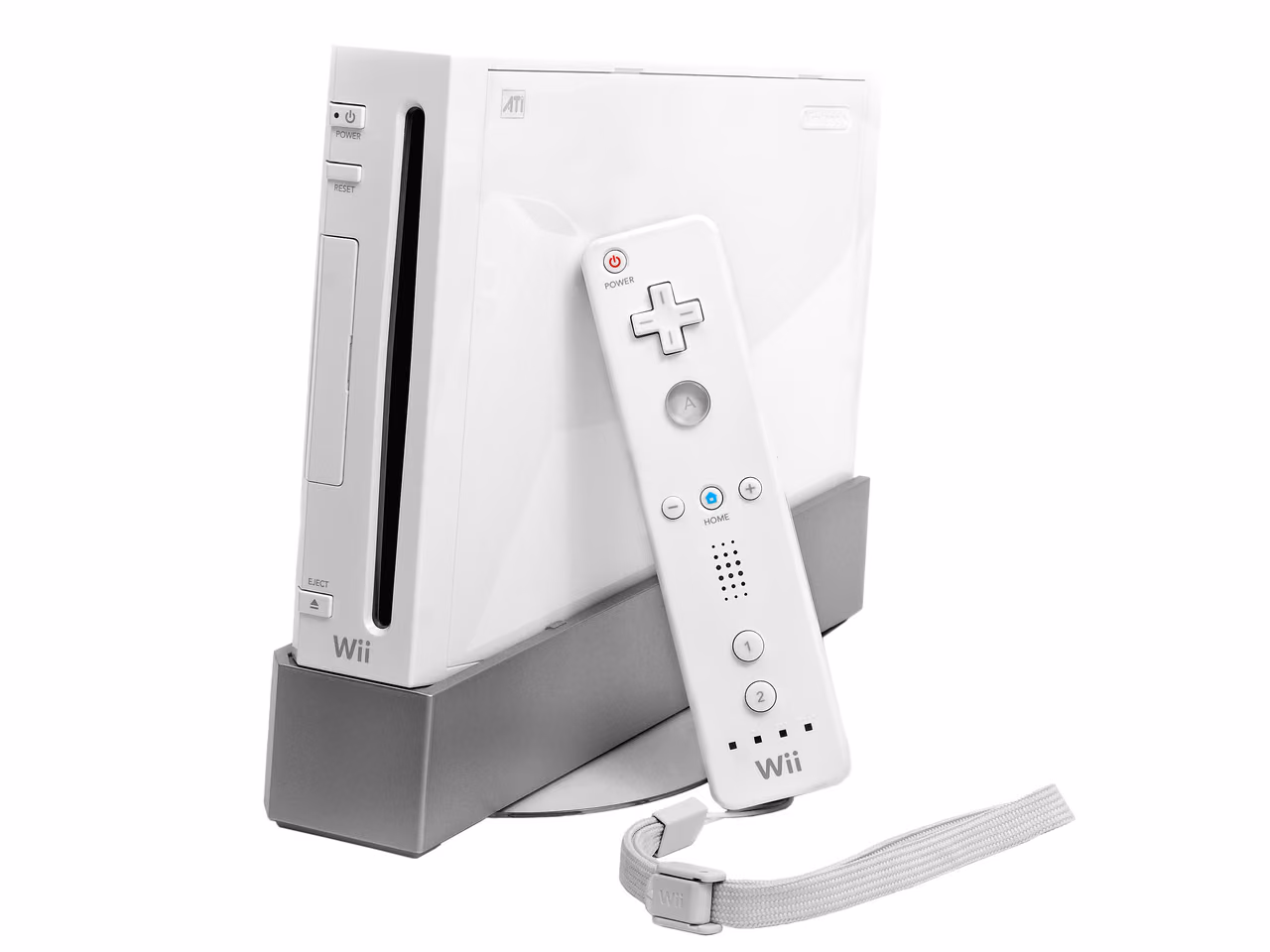 A white Nintendo Wii standing upright in a gray stand and photographed against white, the disc slot running down its front edge, with a Wii Remote and its wrist strap leaning against the console.