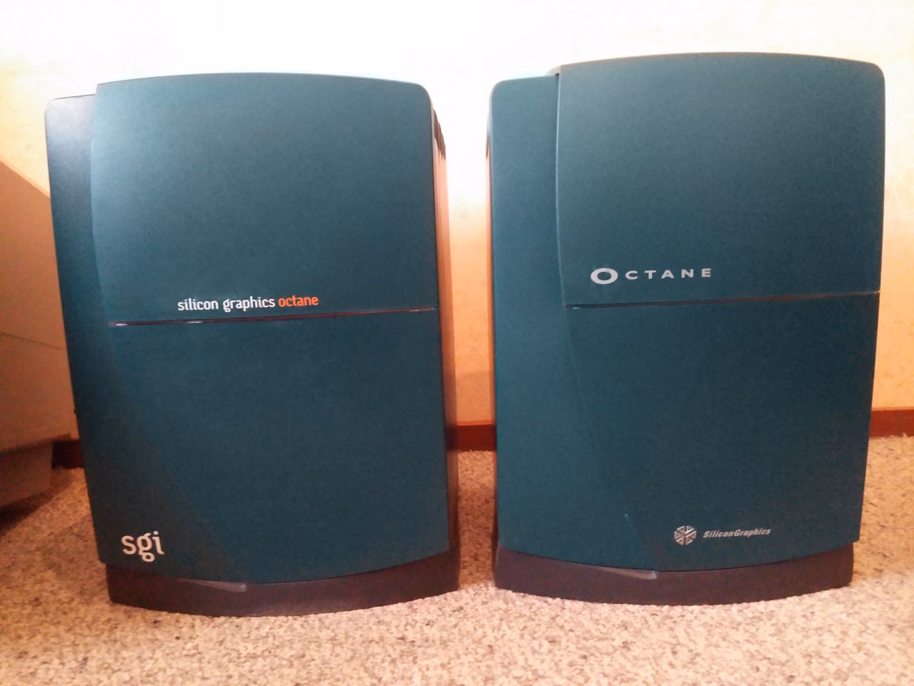 Two Silicon Graphics Octane workstations side by side on a carpet: upright teal cases with a curved seam down the front, the left one lettered 'silicon graphics octane' and the right one 'OCTANE'.